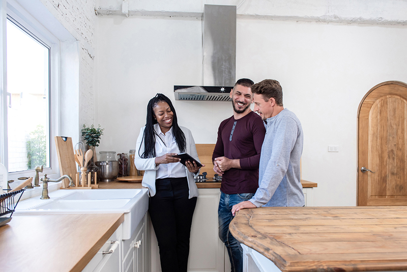 Female real estate agent showing gay couple around new house