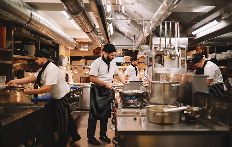 Four cooks in a restaurant kitchen working at different stations