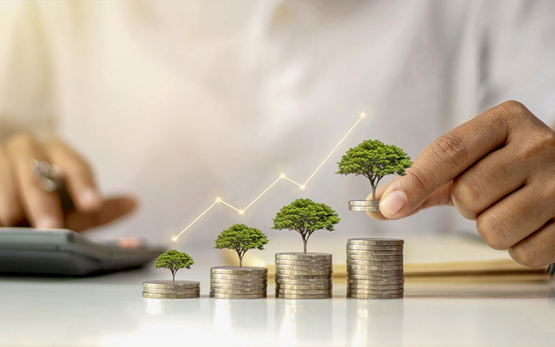 A businessman holding a coin with a tree that grows and a tree that grows on a pile of money. The idea of maximizing the profit from the business investment.