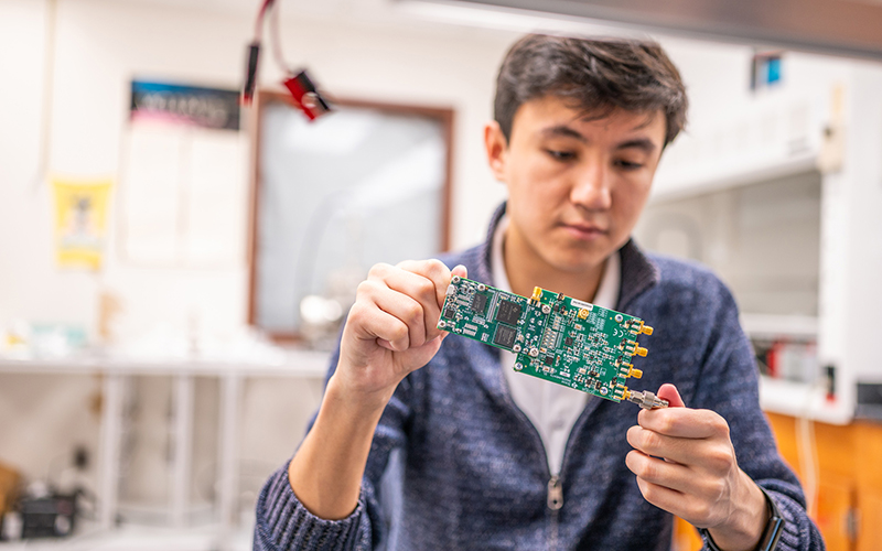 Dimash Aimurzayev, a master’s student in electrical engineering at MSU, examines a circuit board. Electronics like this will be tested at the new Space Electronics Center. // Photo by Derrick L. Turner/MSU