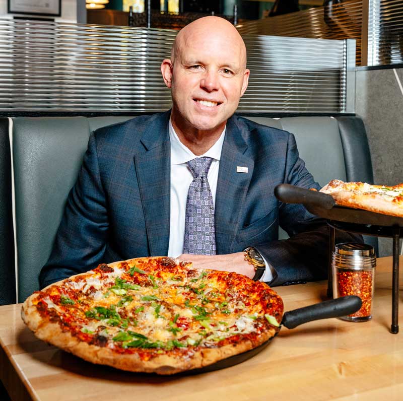 Man in suit in front of pizza